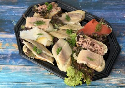 Canapés mit Baguette-Häppchen aus Räucherlachs, Räucherfisch, Nordseekrabben und Graved-Sockeye-Lachs auf schwarzem Tablett