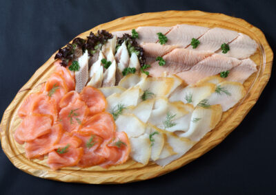 Edelfischplatte mit irischem Lachs, Lachsforellen-Filet, Lachs-Butt und Räucher-Aal-Filet auf ovalem Holzbrett