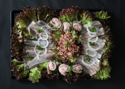 Matjesplatte mit Matjesfilets, gefüllten Matjes-Röllchen mit Preiselbeeren und Nordsee-Krabbenfleisch auf schwarzem Tablett