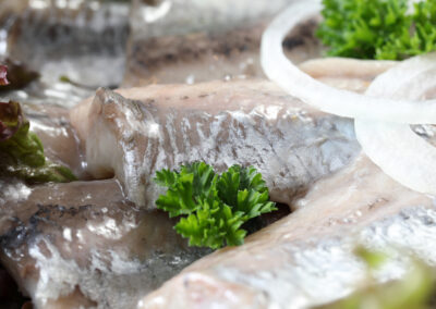 Nahaufnahme eines Matjesfilets mit Petersilie und Zwiebelringen, Matjesplatte der Wuppertaler Fischkultur