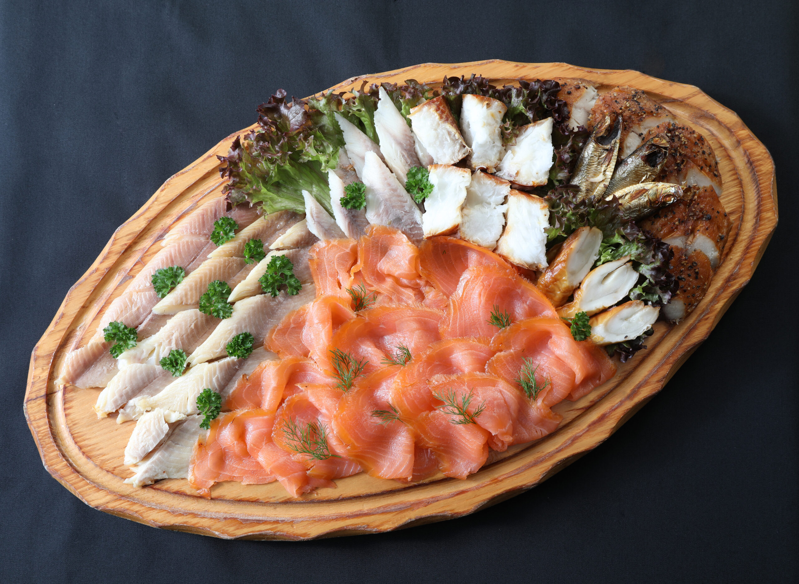 Fischplatte "Querschnitt durch die Theke" mit Forellenfilet, Irischem Räucherlachs, Heilbutt, Makrele und Schillerlocken auf Holzbrett