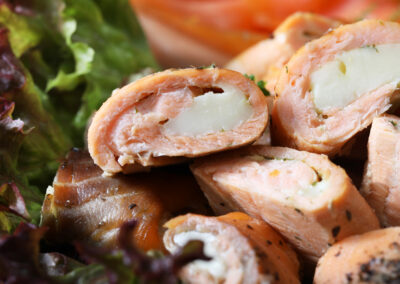 Aufgeschnittene Lachsrouladen mit cremiger Füllung auf dem Feinschmecker-Fischbrett "Vom Feinsten"