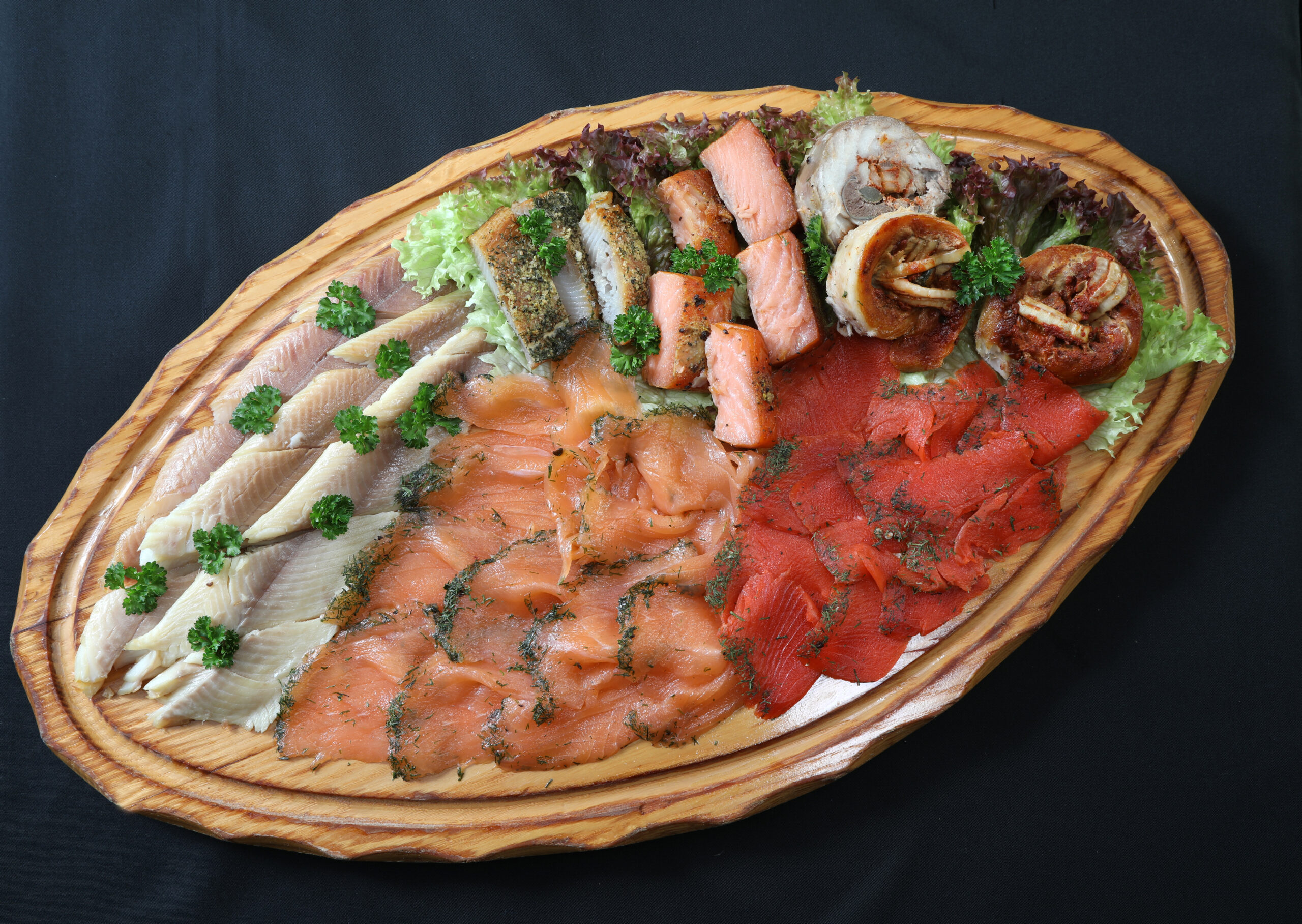 Würziges Spezialitätenbrett mit Aalfilet, gereiftem Lachs, Wikingerlachs, Kräuter-Butt und Zwiebel-Möpsen auf ovalem Holzbrett