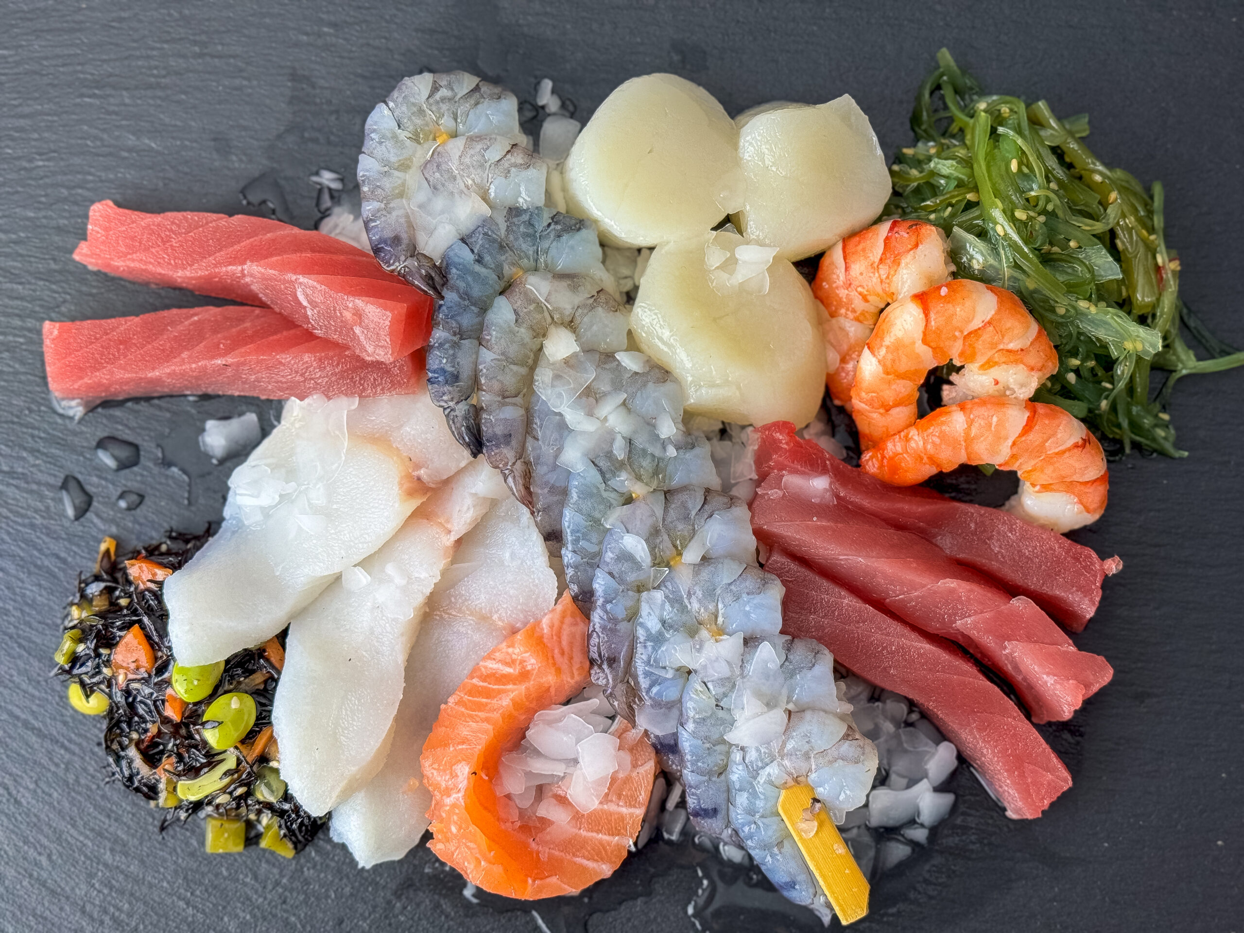 Sashimi-fein geschnittene Fisch- und Meeresfrüchte-Auswahl aus der Fisch- und Feinkosttheke der Wuppertaler Fischkultur: Thunfisch, Lachs, weißer Fisch, Garnelen und Jakobsmuscheln auf Eis, dazu marinierter Algensalat