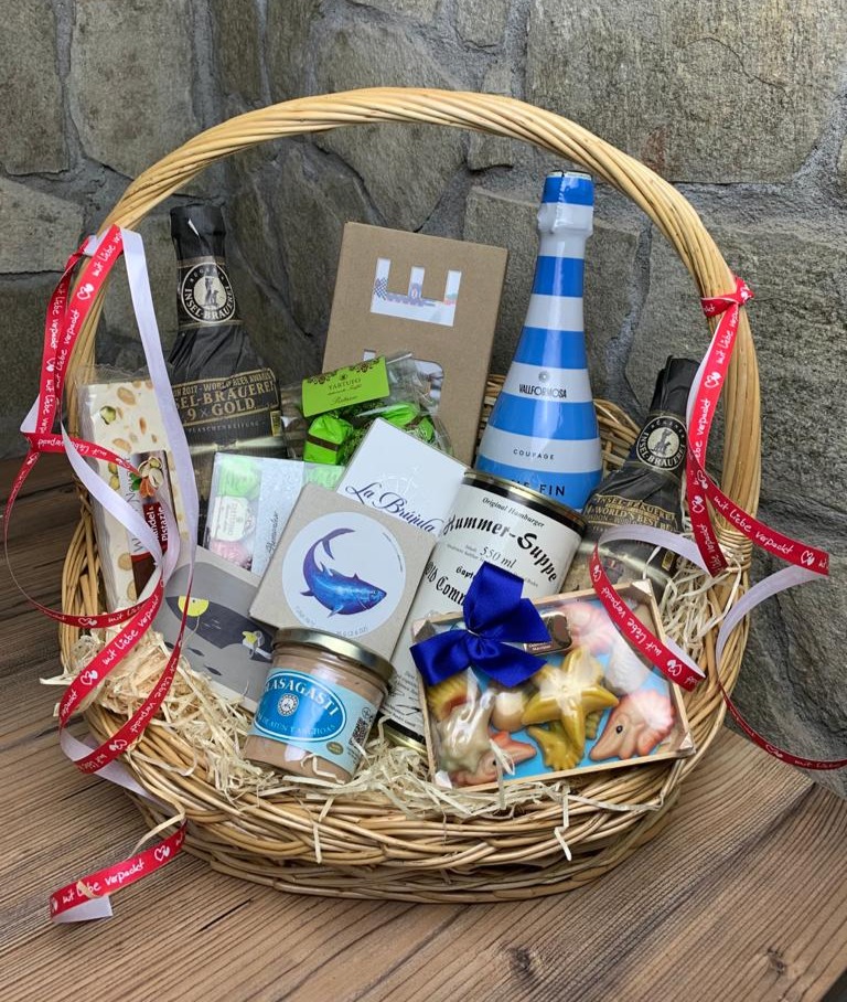 Geschenkkorb mit Feinkost, Hummersuppe, Sekt und Delikatessen vor Natursteinwand