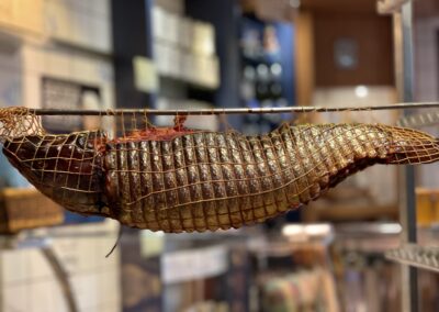 Ganzer Räucherlachs im Räuchernetz beim Reifen in der Fischräucherei