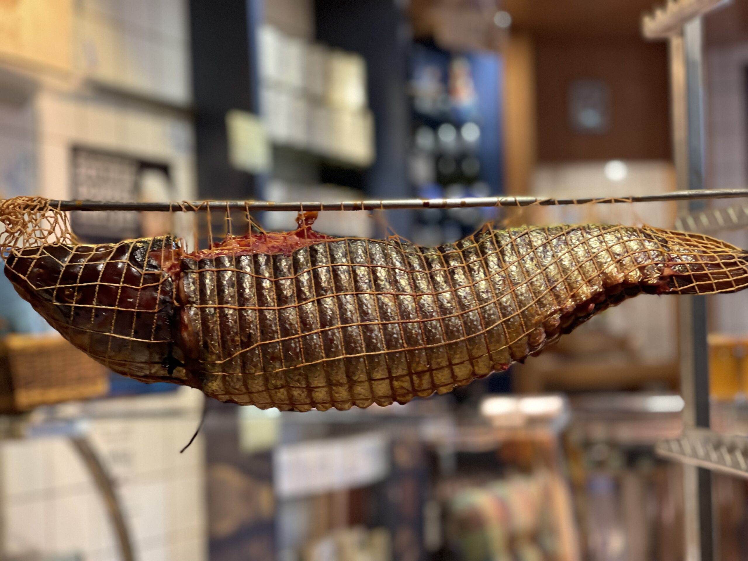 Ganzer Räucherlachs im Räuchernetz beim Reifen in der Fischräucherei